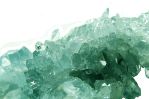 fraud and misconduct investigations - Close-up of translucent blue-green crystals on a white background.